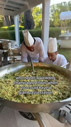 two chefs in white hats are preparing food on a large metal pan with words written below it