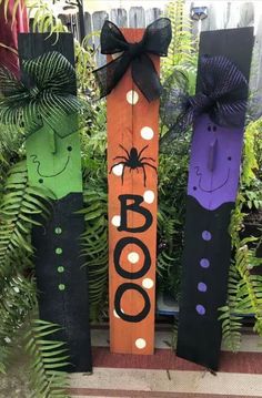 three halloween decorations made out of wooden sticks with faces on them and the word boo spelled in