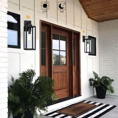 the front door is decorated with black and white striped rugs, potted plants, and lanterns