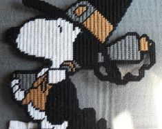 a cross stitch bead pattern of a dog with a hat on its head holding a skateboard