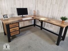 a desk with a computer monitor and keyboard sitting on it's side, in front of a wooden paneled wall