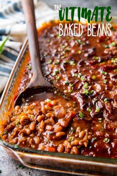 the ultimate baked beans recipe in a casserole dish with a wooden spoon on top