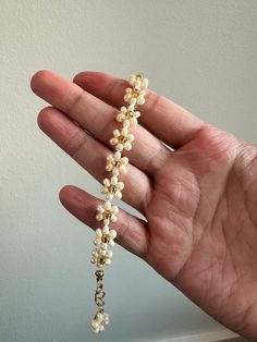 An elegant, hand-made, daisy beaded bracelet in a pearl luster finish with a gold flower center. Gold hardware utilized, finished with a cute flower charm at the end! Hand-made to order! Made in a smoke-free and pet-free environment! Lengths vary in sizes. There are 8 different length options available. Lengths range from 13cm to 20cm in length, and can vary even further depending on which jump-ring you clamp the lobster claw to. Handmade White Pearl Bracelet With Flower Shape, Handmade White Pearl Flower Bracelet, Handmade White Flower Pearl Bracelet, Gold Pearl Flower Bracelets, Handmade Delicate Pearl Bracelet With Flower Shape, Handmade Delicate Pearl Bracelet With Flower Design, Delicate Handmade Flower Pearl Bracelet, Adjustable Flower-shaped Pearl Bracelet, Dainty Flower Pearl Beaded Bracelets