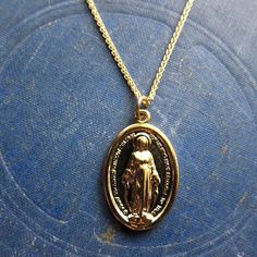 The Lady Madonna Necklace features a a high quality 14k gold wheat chain with a classic oval Mother Mary / Virgin Mary / Miraculous Mary Medal religious pendant. Perfect for layering!Chain: 14k Gold Fill Wheat Chain - 18" with a 2" extender.Pendant: Measures 15mm x 23mmMaterial:14k Gold Over BrassHandmade in NYC✦ GOLD FILL CARE ✦✧ Warm water and a soft cloth are the best thing you can do to maintain the beauty of your jewelry.✧ Jewelry polishing cloths work great and are non-abrasive.✧ Salt wate Spiritual Yellow Gold Oval Necklace, Spiritual Oval Yellow Gold Necklace, 14k Gold Necklace With Miraculous Medal, Yellow Gold Necklace With Miraculous Medal, 14k Yellow Gold Miraculous Medal Necklace, Yellow Gold Miraculous Medal Oval Pendant Necklace, Yellow Gold Oval Pendant Necklace With Miraculous Medal, 14k Yellow Gold Necklace With Miraculous Medal, Yellow Gold Necklace With Miraculous Medal Round Pendant