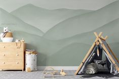 a child's room with a teepee tent and mountains painted on the wall