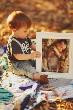 a little boy sitting on the ground with a picture frame in front of his face