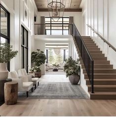 a living room filled with lots of furniture next to a stair case and potted plants