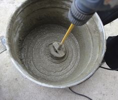 a person pouring cement into a bucket