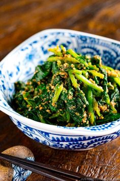 a blue and white bowl filled with green vegetables