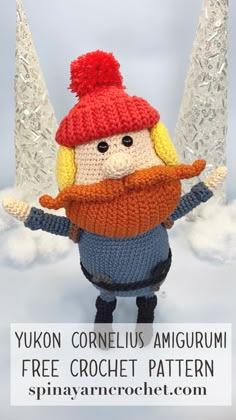 a crocheted doll with a red hat and scarf is standing in the snow