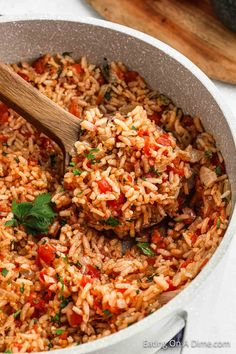 a pot full of rice and vegetables with a wooden spoon