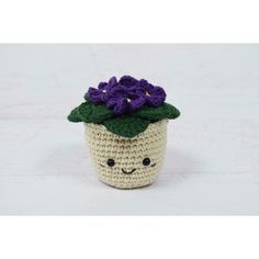 a small crocheted cupcake with purple flowers on it's head and eyes