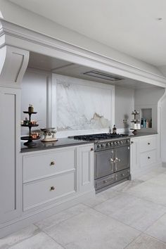 a large kitchen with marble counter tops and white cabinetry, along with stainless steel appliances