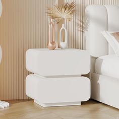 two white vases sitting on top of a nightstand next to a bed with pillows