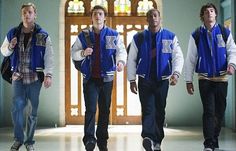 three young men are walking down the hall in their blue vests and plaid shirts