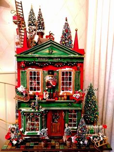 a green and red doll house with christmas decorations on the front, windows, and stairs