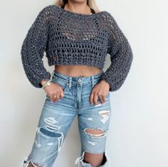 a woman in ripped jeans and a crop top posing for the camera with her hands on her hips