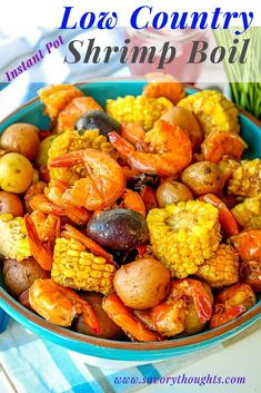 a bowl filled with shrimp, corn and potatoes on top of a blue table cloth