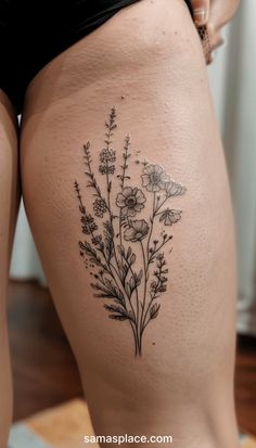 a woman's thigh with flowers and leaves tattooed on the back of her thighs