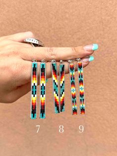 a woman's hand holding four multicolored beaded bracelets