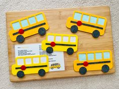 four yellow school buses are on a wooden board