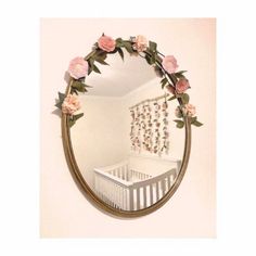 there is a mirror that has flowers on the wall above it and a crib in the background