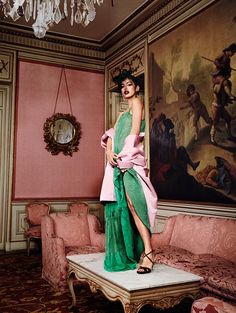 a woman in a green and pink dress standing on a table