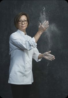 a woman in white shirt and black pants holding out her hands with water coming out of it