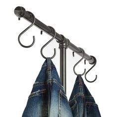 two pairs of jeans hanging on a metal pole with hooks and clothes hangers in front of them