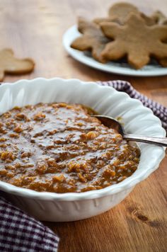 a white bowl filled with food sitting on top of a wooden table next to cookies