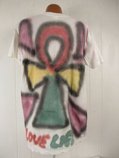 "Vintage 1990s primitive outsider or folk art style t shirt. Made of white cotton with 2 sided air brushed graphics. Has large portrait on the front and symbol on back. Reads: Come back Jesus Love Life. Signed: Loren A. Evans 91. Size extra large. Actual measurements are: 46\" around the chest 46\" around the waist 22\" shoulder seam to shoulder seam 32\" overall length In excellent condition." Bohemian Cotton T-shirt For Streetwear, White Relaxed Fit T-shirt For Festival, Vintage Hand Printed Short Sleeve T-shirt, Vintage Hand-printed Short Sleeve T-shirt, Artsy White Graffiti Print Top, Vintage Cotton T-shirt For Festival, White Artsy Graffiti Print Top, Bohemian Short Sleeve T-shirt For Streetwear, Artistic Cotton T-shirt With Graffiti Print