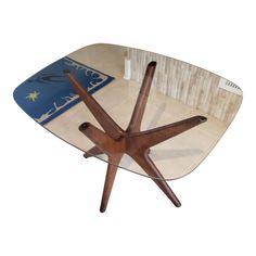 a glass table with wooden legs and a surfboard on it's back end