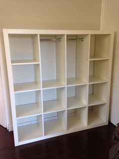 an empty white bookcase in the corner of a room