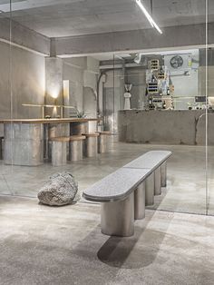 a bench sitting in the middle of a room with large rocks on the floor and tables behind it