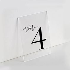 a table number with the number four in black ink on a clear acrylic sheet