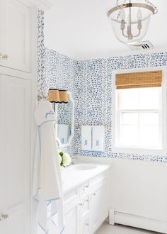 a bathroom with blue and white wallpaper, sink, mirror and light hanging from the ceiling