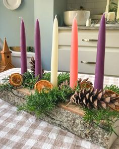 some candles are sitting on a table with pine cones and oranges