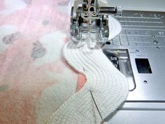 the sewing machine is working on the pink and white fabric that has been sewn