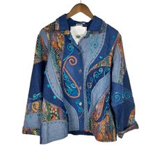 a blue jacket with paisley designs on it and a white shirt hanging from a wooden hanger