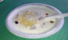 a white bowl filled with food on top of a green tablecloth next to a plastic spoon