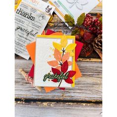 some cards are laying on top of a wooden table with autumn leaves and other items