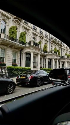 cars are parked on the side of the road in front of an apartment building with balconies