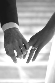 the bride and groom hold hands as they stand close to each other with their wedding rings on their fingers