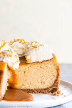 a piece of cheesecake on a plate with caramel sauce and whipped cream topping