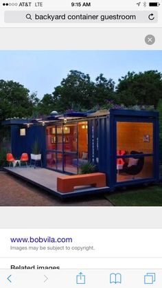 a house made out of shipping containers sitting on top of a lush green field next to trees