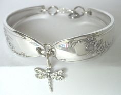 a silver bracelet with a cross on the side and a dragon charm hanging from it