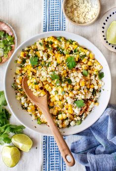 a white bowl filled with corn and cilantro on top of a blue towel