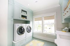 a washer and dryer in a large room with two windows on the wall