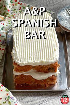 a square cake with white frosting on a metal tray next to a fork and napkin