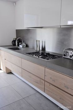 a kitchen with white cabinets and gray counter tops, along with a stove top oven